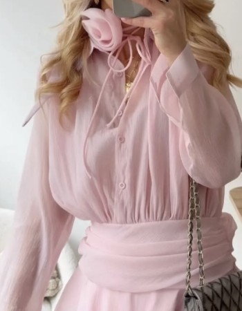 Ρομαντικό φόρεμα σε απαλό ροζ, με δέσιμο στο λαιμό και εντυπωσιακό λουλούδι. Αέρινη γραμμή, κουμπιά μπροστά και ζώνη στη μέση που αναδεικνύει τη σιλουέτα.