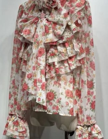 Αέρινη μπλούζα με ρομαντικό floral print σε αποχρώσεις ροζ, διακοσμημένη με εντυπωσιακά βολάν και φιόγκο μπροστά. Διαθέτει ιδιαίτερες λεπτομέρειες στον γιακά με τριαντάφυλλα και μακριά μανίκια με βολάν στο τελείωμα