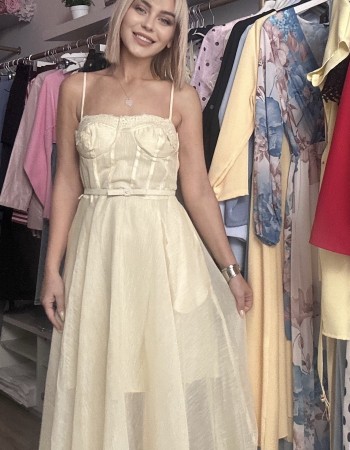   τιράντες και ενισχυμένο μπούστο τύπου κορσέ που αγκαλιάζει υπέροχα το σώμα, ενώ η διακριτική ζώνη στη μέση τονίζει τη σιλουέτα. Η ανάλαφρη φούστα με διαφάνειες και δαντελένιες λεπτομέρειες στο τελείωμα χαρίζει κίνηση και κομψότητα σε κάθε βήμα.